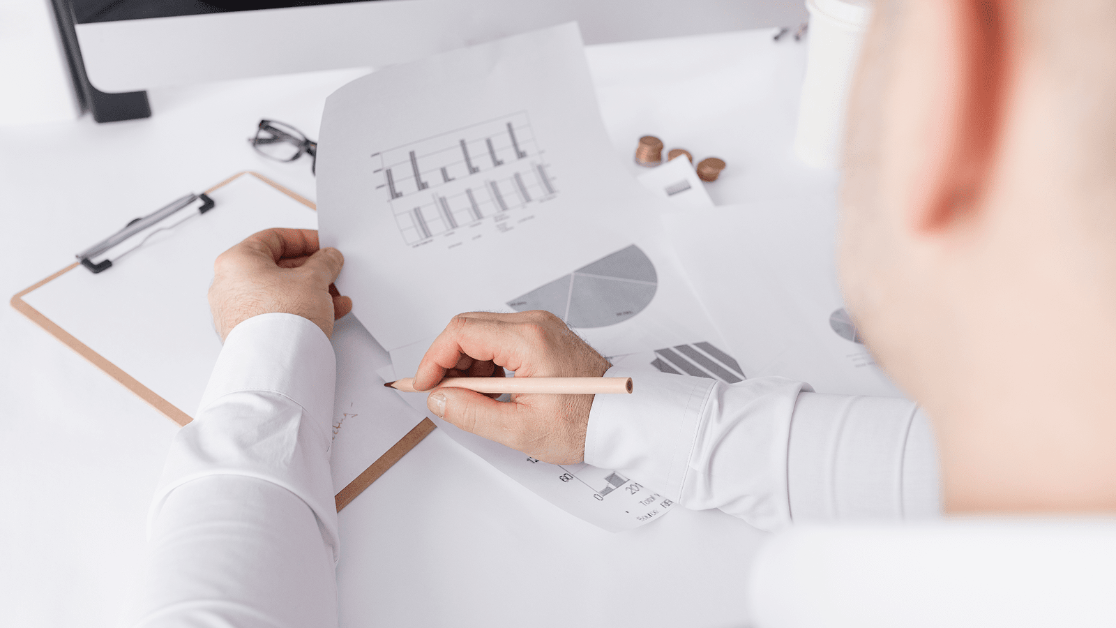 Мужчина просматривает распечатанные графики и делает пометки карандашом