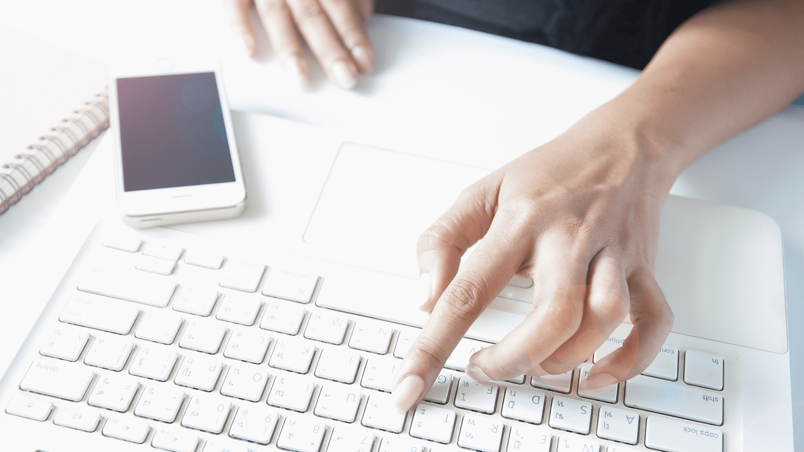 Человек набирает текст для страницы «Контакты» на ноутбуке, рядом смартфон