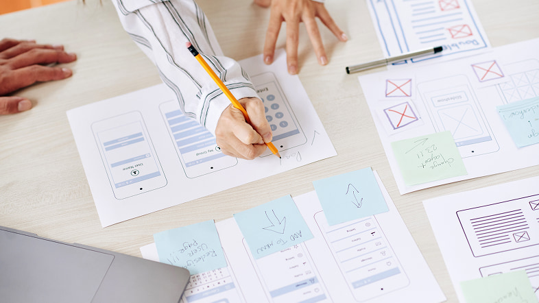 Люди обсуждают наброски страниц на листах при подготовке замысла