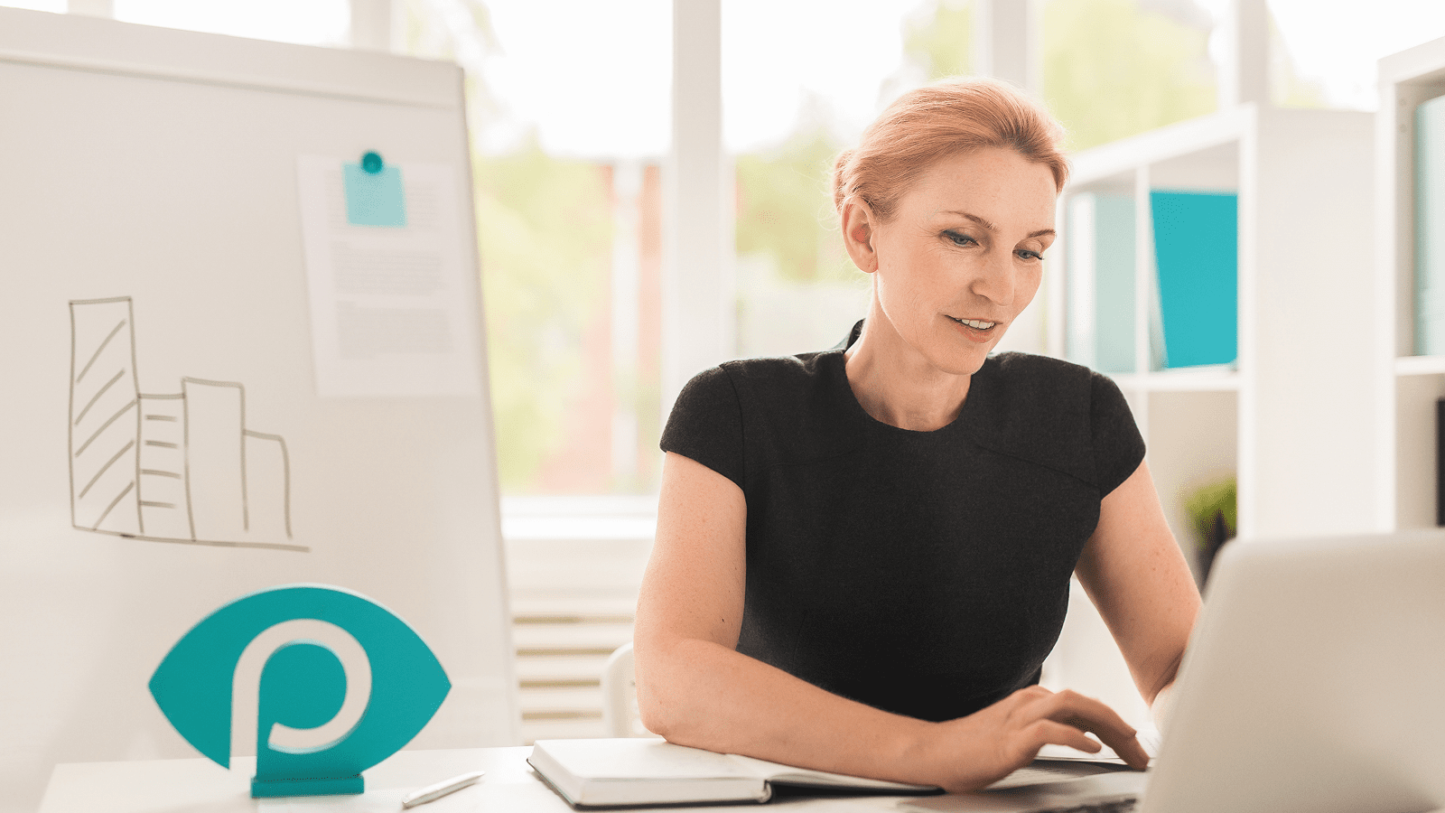 Женщина работает за ноутбуком в офисе с доской для заметок