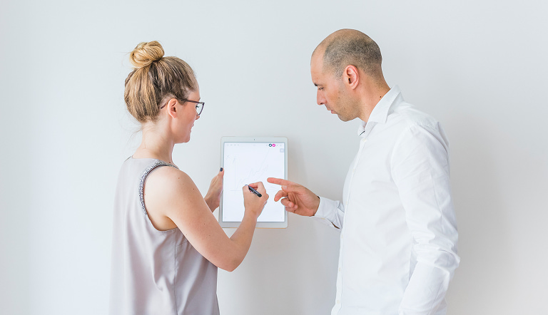 Мужчина и женщина обсуждают рисунок роста у светлой стены