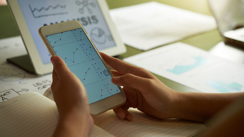 Человек анализирует графики на смартфоне при проектировании структуры приложения