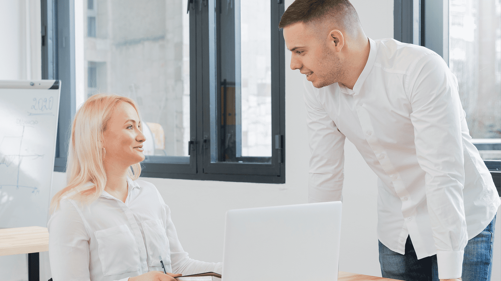 Менеджер обсуждает маркетинговое предложение с коллегой у ноутбука в офисе