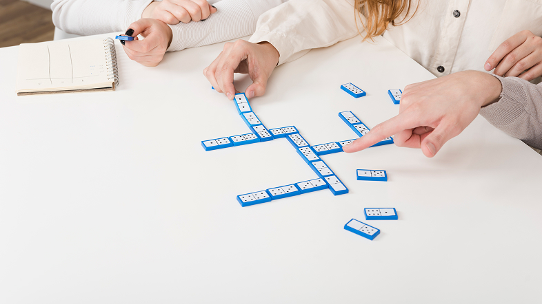Люди выкладывают игральные костяшки на столе, обсуждая порядок расположения