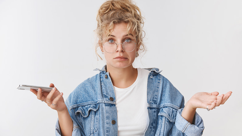 Девушка со смартфоном разводит руками в недоумении
