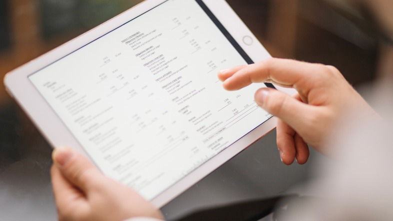 Руки человека, держащего планшет с таблицей данных на экране