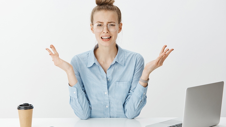 Растерянная женщина за столом разводит руками перед началом работы