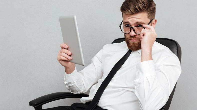 Мужчина с планшетом в кресле смотрит с недоумением