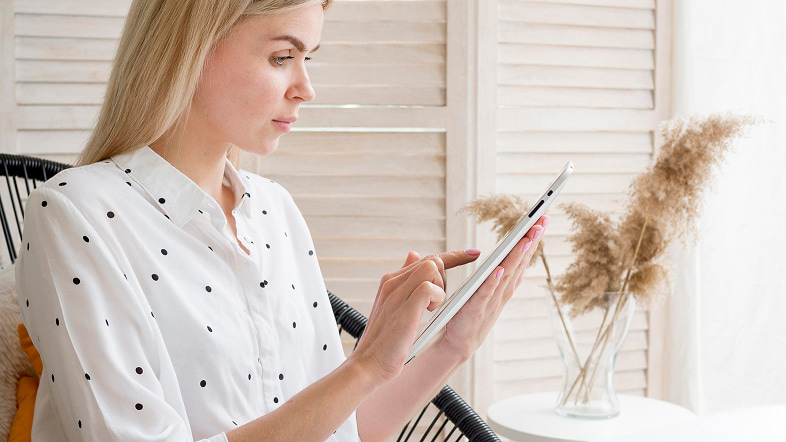 Женщина читает с планшета в светлой комнате