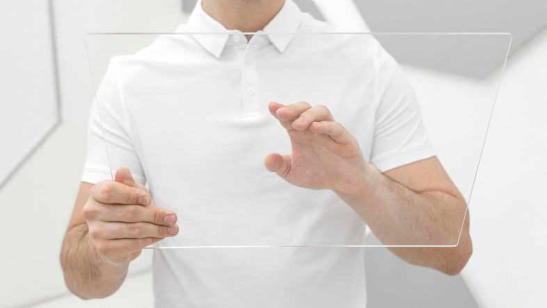 Человек держит прозрачную панель и касается цифрового интерфейса