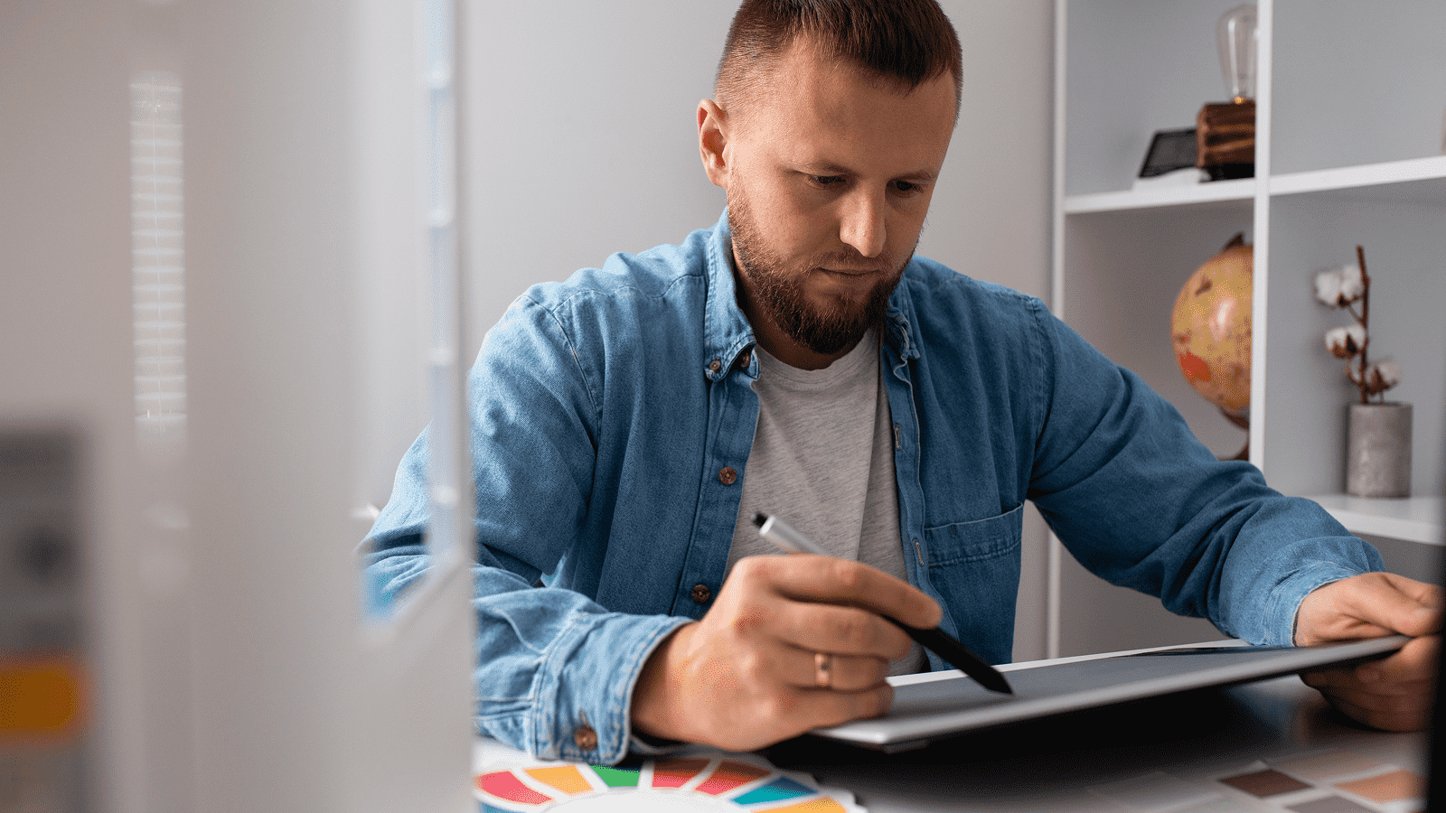 Веб-дизайнер за графическим планшетом с цветовыми палитрами на столе