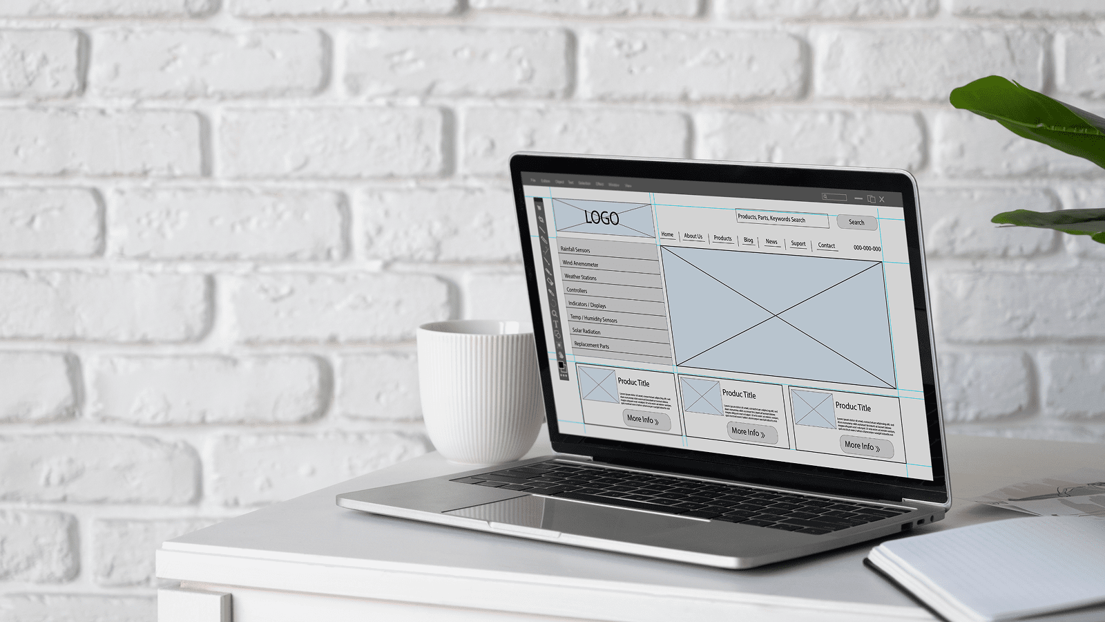 Ноутбук с макетом страницы сайта на столе, рядом блокнот и чашка.