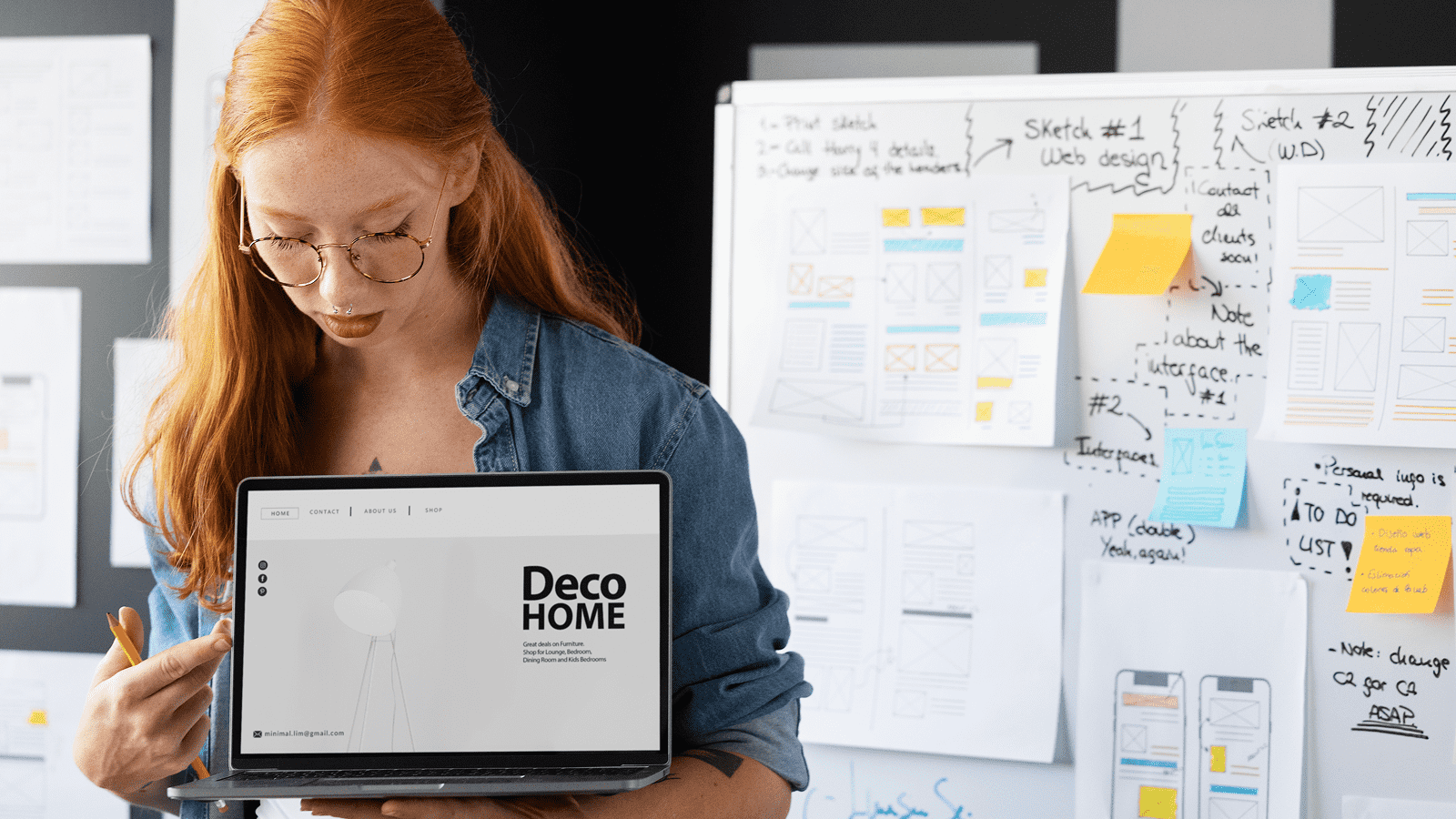 Женщина с ноутбуком показывает веб-портфолио на фоне макетов и заметок