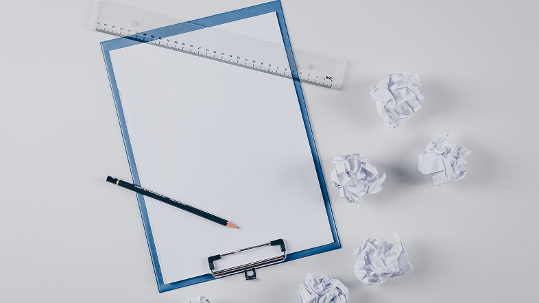 Чистый лист на зажиме, мерная планка и скомканная бумага