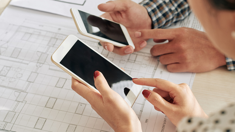 Люди держат переносные устройства над планом помещения