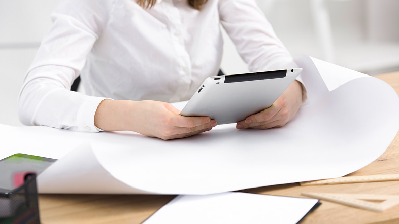 Человек держит планшет на фоне светлых цветов