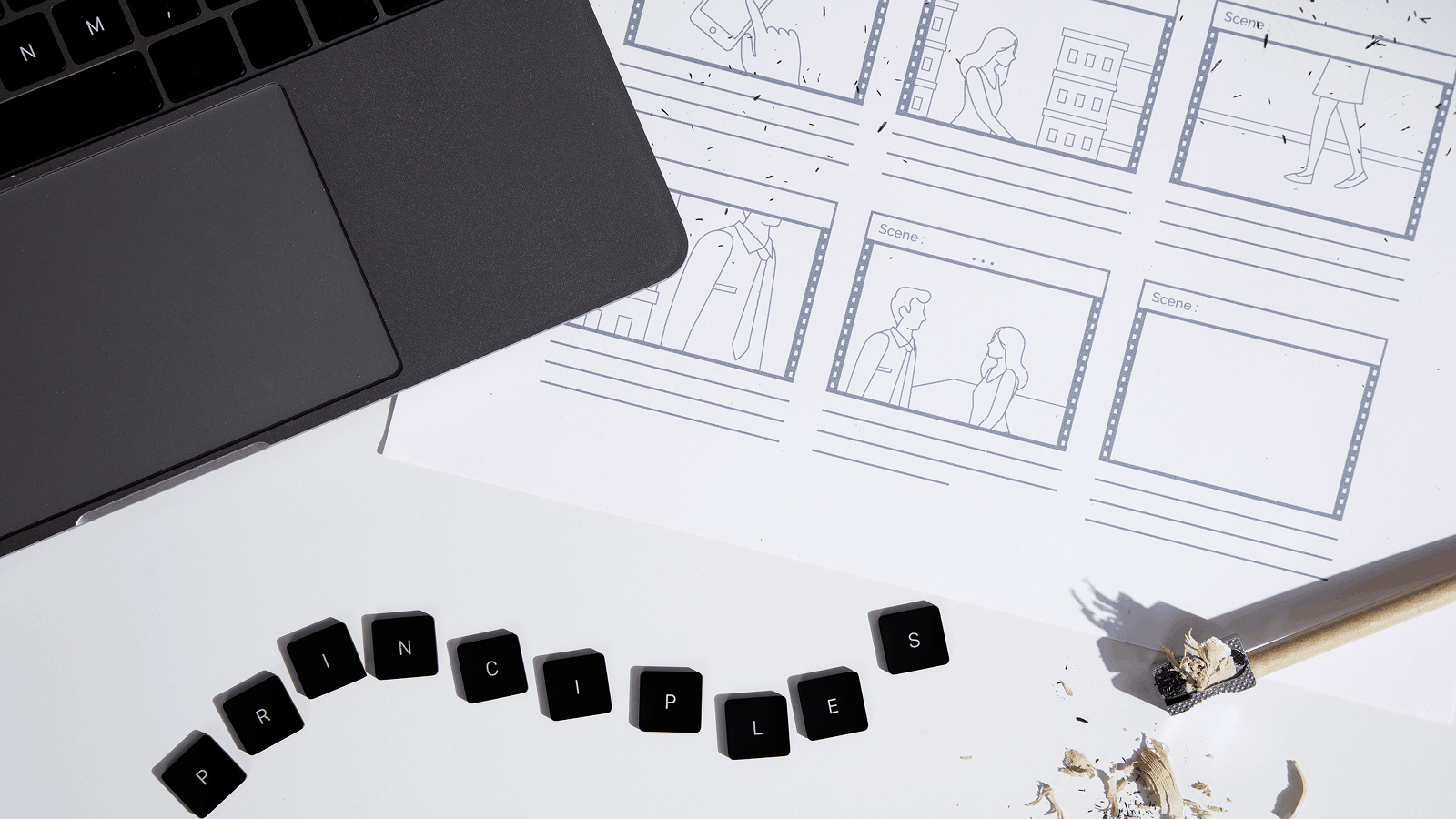 Рабочее место дизайнера: ноутбук, раскадровки интерфейса, карандаш и стружка