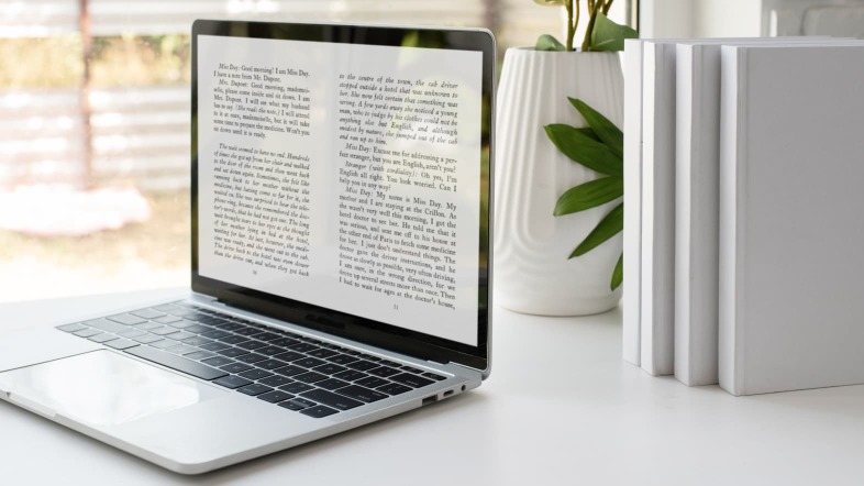 Открытый ноутбук на рабочем столе рядом с белой книгой